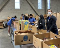 people in warehouse sorting through cardboard boxes