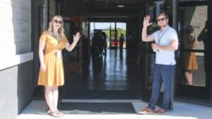 woman and man by open office building door waving