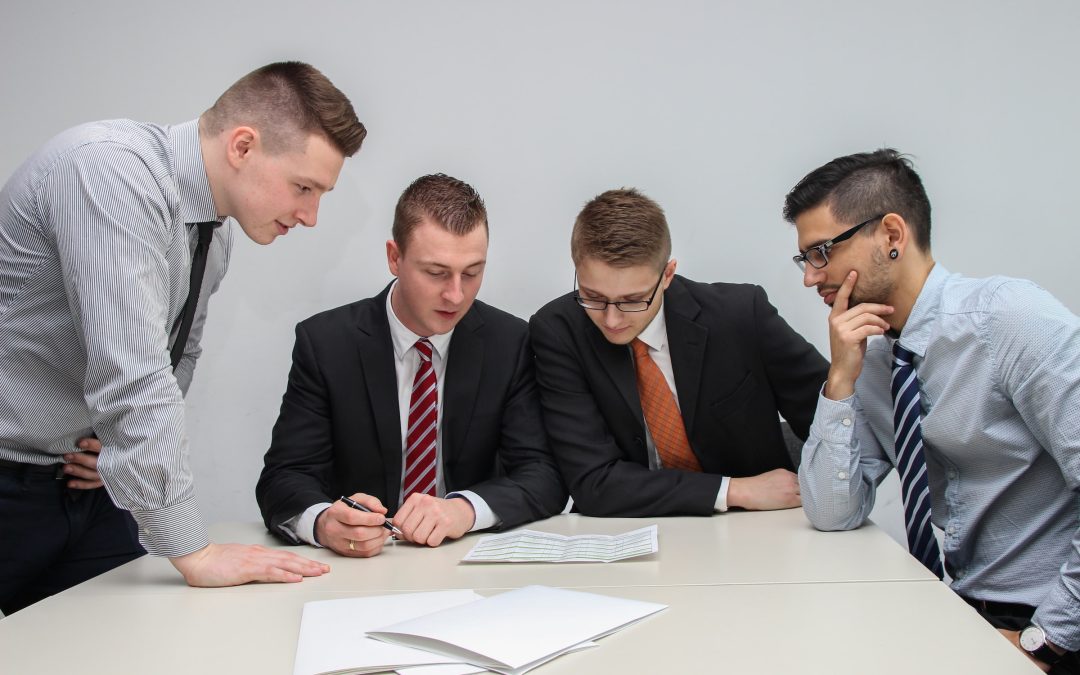4 business men at conference table looking at papers