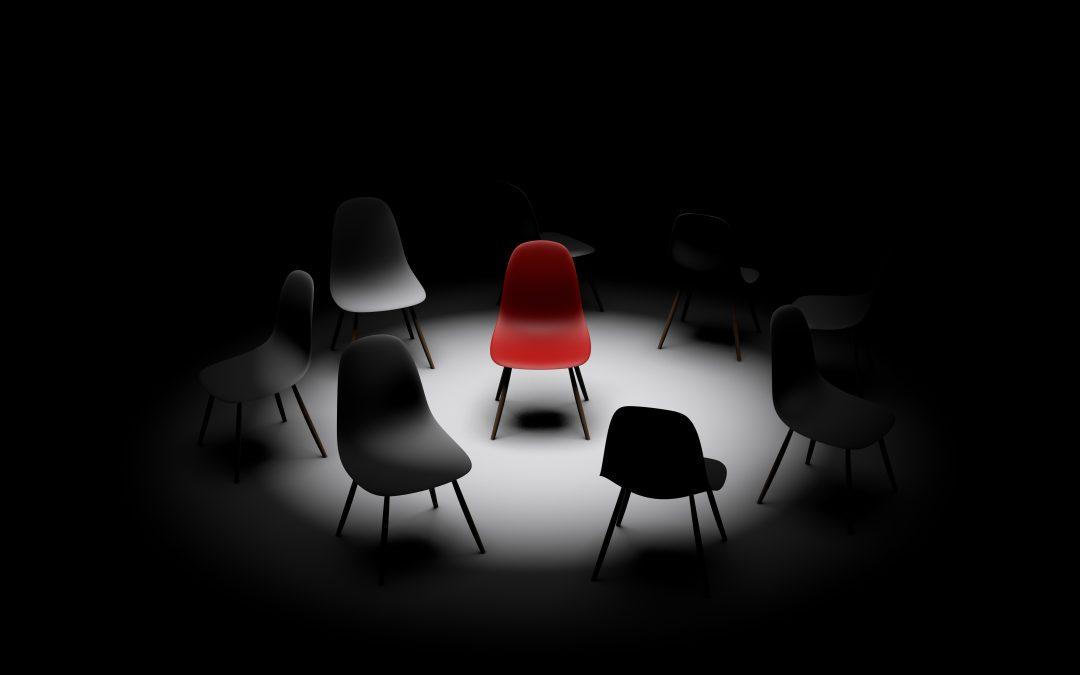 red chair under light surrounded by black chairs