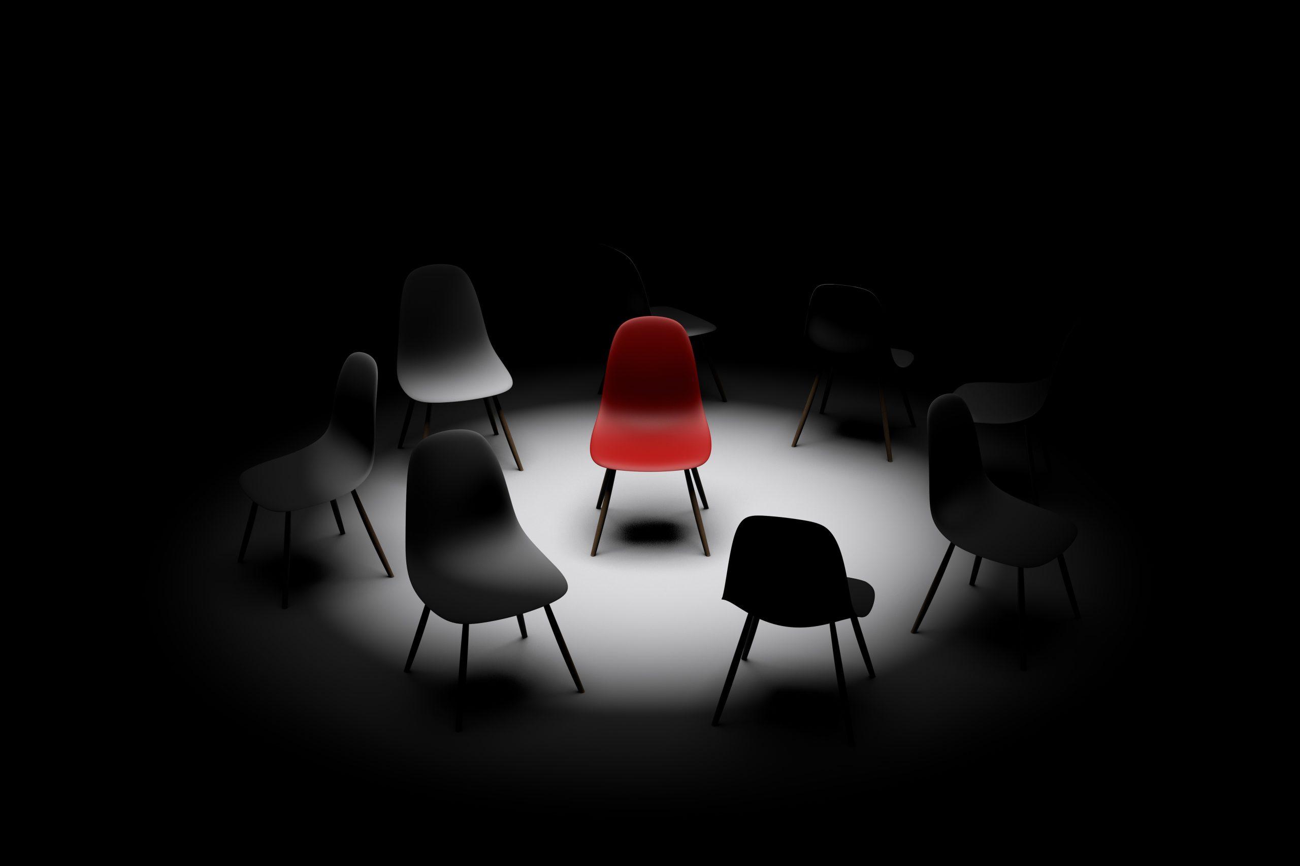 red chair under light surrounded by black chairs
